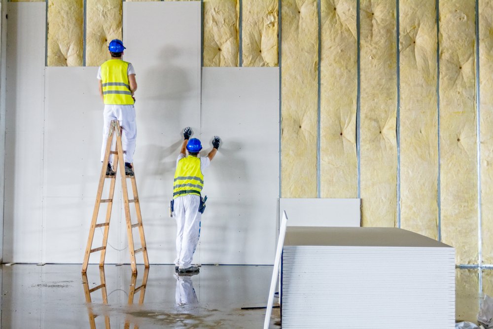 Trabajadores instalando paneles de tablaroca sobre estructura con aislamiento