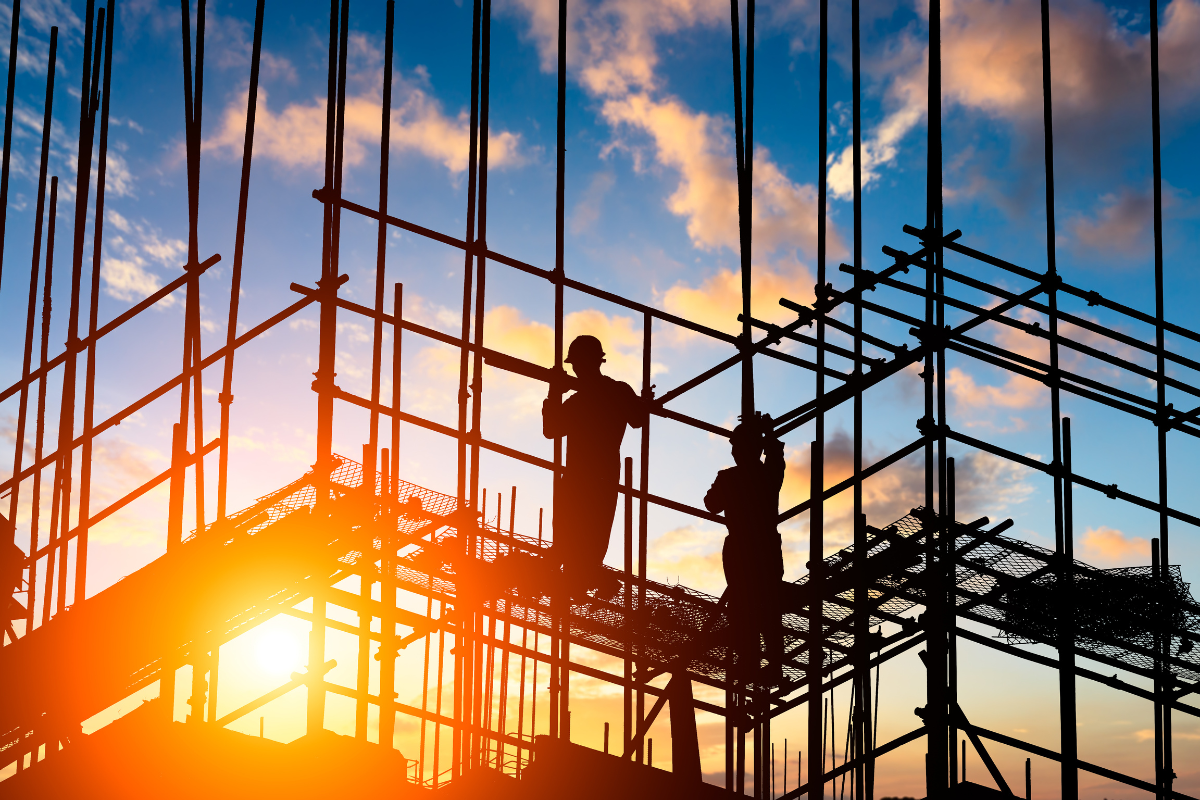 Trabajadores sobre andamiaje de una obra en construcción, al atardecer